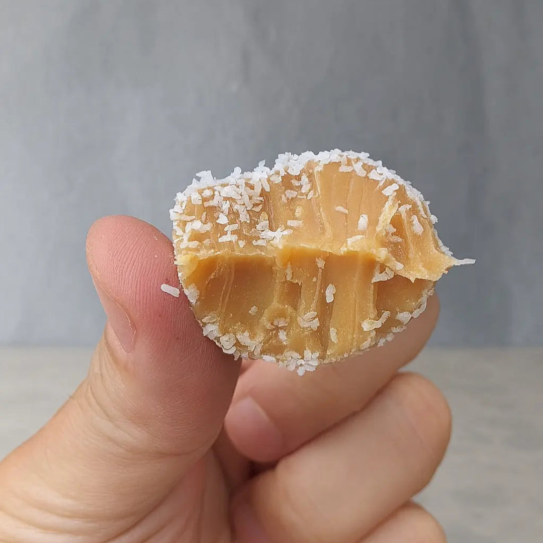 Cocadas Keto con una mordida sin gluten, sin azúcar y bajas en carbohidratos, rellenas con manjar keto y coco natural.